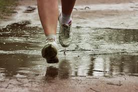 Runner running through puddle